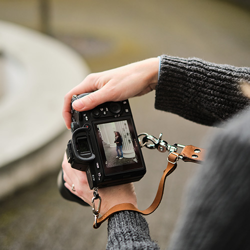Nahaufnahme einer Kamera in den Händen der Fotografin Annika Rose – auf dem Display ist ein Porträt einer Frau vor einer Säule zu sehen.