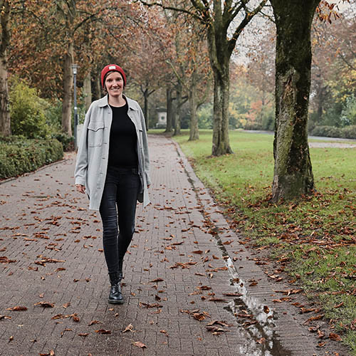 Fotografin Annika Rose spaziert lächelnd auf einem herbstlichen Weg auf dem Lemgoer Wall, umgeben von buntem Laub und Bäumen.